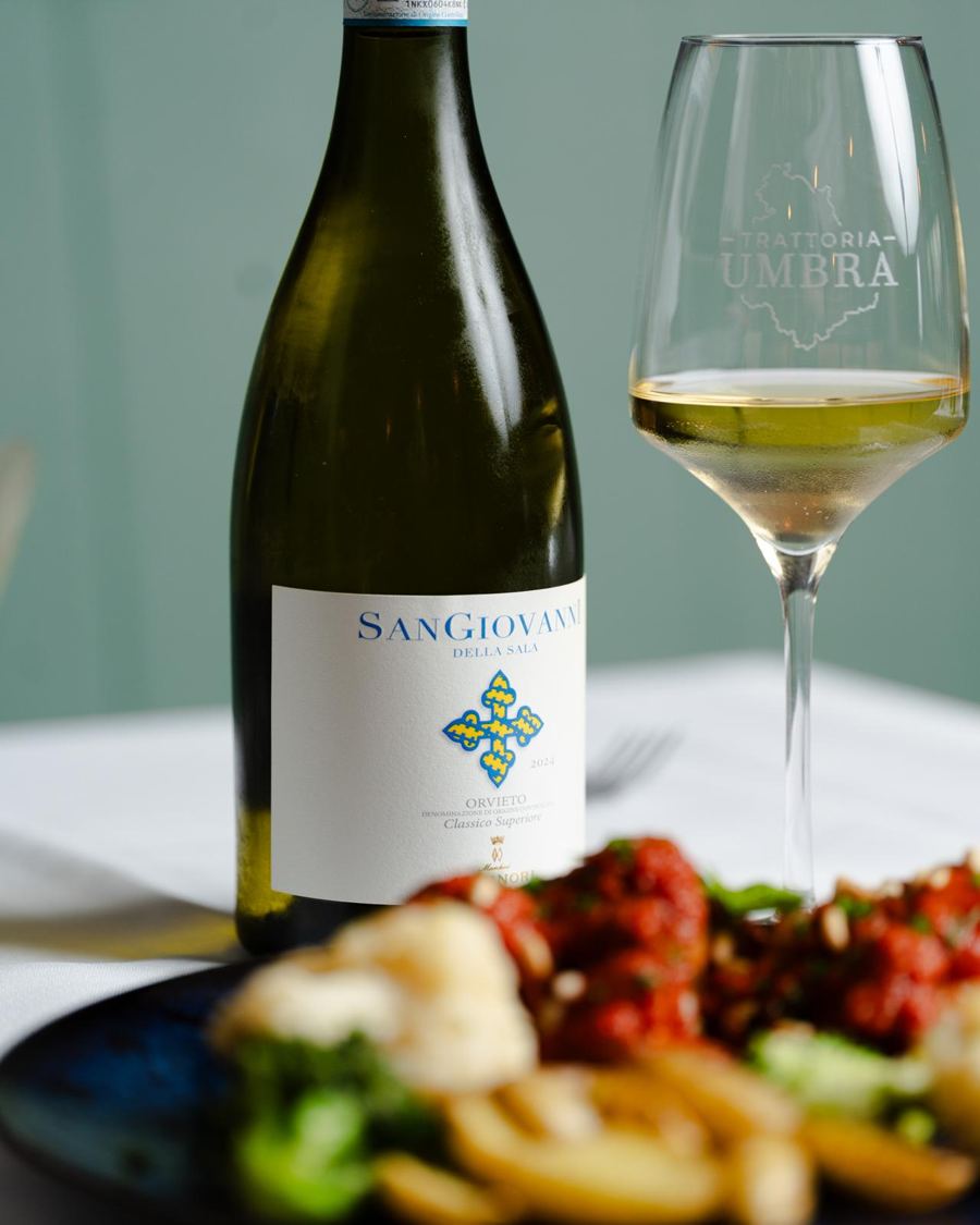 Fles en glas San Giovanni met een bord gerechten